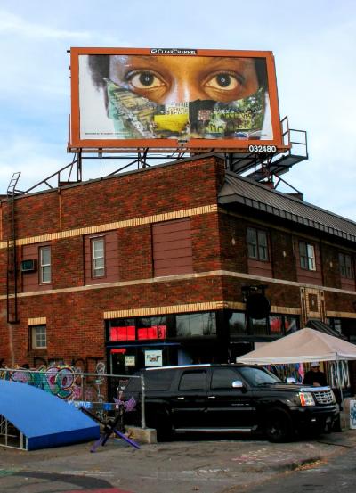 A billboard of a person in a mask over a brick building